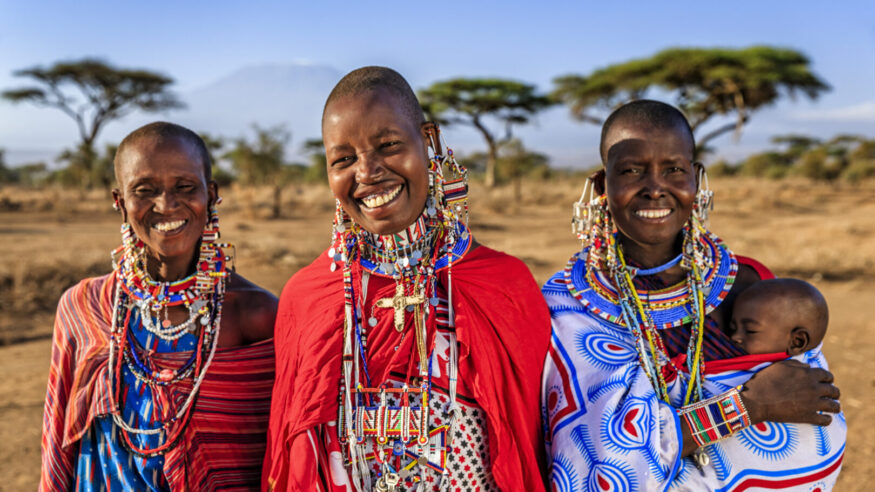 African mother from Maasai tribe carrying her baby , Kenya, Africa - Mount Kilimanjaro on the background. Maasai tribe inhabiting southern Kenya and northern Tanzania, and they are related to the Samburu.