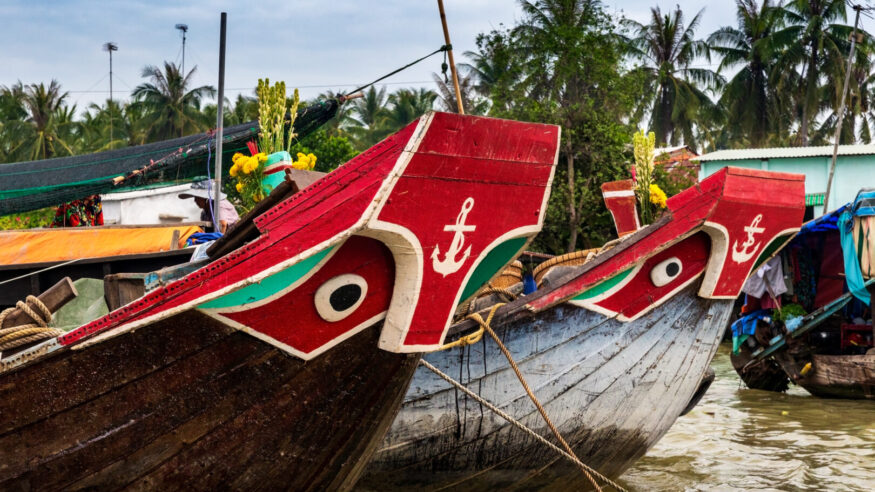 Two wooden boats with eyes and anchor painting decoration on the prow.Anchored in the muddy waters of the Mekong Delta near the town on Can Tho, Vietnam.
