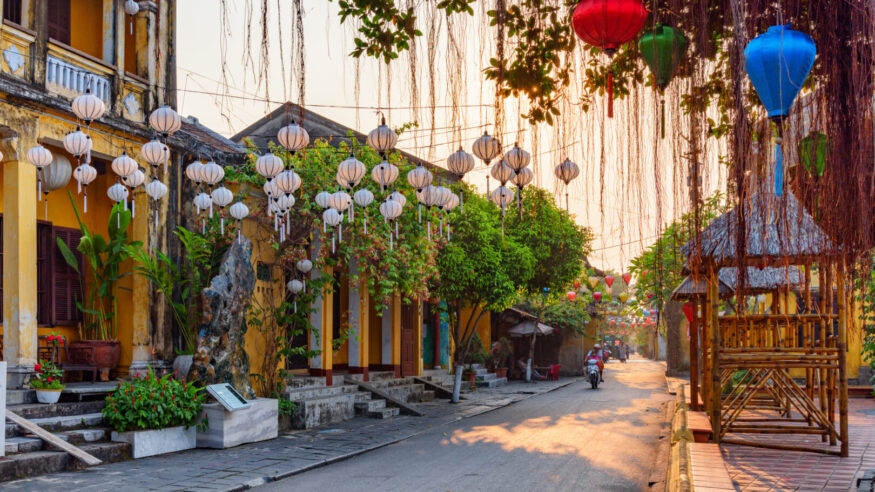 Gorgeous view of cozy street decorated with colorful silk lanterns at sunrise. Scenic traditional old yellow houses of Hoi An Ancient Town, Vietnam. Hoian is a popular tourist destination of Asia.